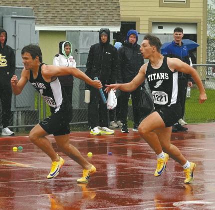 Trenten Bronson-Keena receives the baton from Carter Johnson while navigating slippery track conditions during the 4X100 relay. The team set a new school record of :44.67. Photo by Larry Stokke
