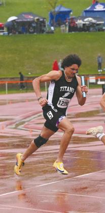 Mason Pollestad grips the baton as he navigates slippery track conditions during the relay. Photo by Ashley Schafer