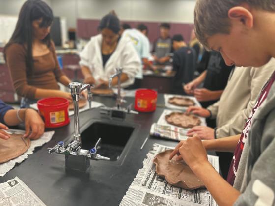 North Valley CTE students Julissa Garcia (left), Daphneiris Almonte, and Aaron Linner press prairie plants into clay plates as part of the Thinking Like a Prairie workshops. Plates will be fired and glazed and used at a potluck as part of the program next Spring. Photo Josh Anderson.