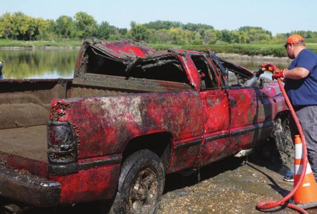 Drayton Fire Chief Jordan Grundstrom washs some of the river mud off of the pickup after it was recovered. VNV Photo by Lyle Van Camp