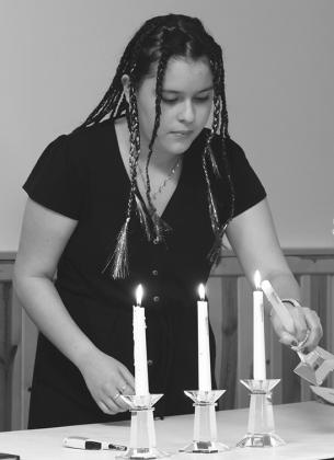 Melissa De Souza lights her candle before reading her part in the National Junior Honor Society Induction Ceremony. Photo by Lyle Van Camp.