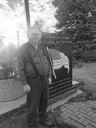 Bellamy stands beside an American Legion Veterans Memorial. Photo by Christine Jensen.