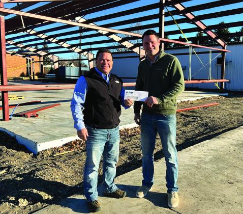 Polar Board Member Dan Johnson (left) presents a check to Hoople Community Fund Committee Member Jeff Olson (right) while standing on the construction site of the new Community Center being built in Hoople.