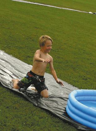 Canaan Smith slides into home at Friday's Slip 'N Slide kickball game at Schumacher Park.Photo by Jamir Rarick