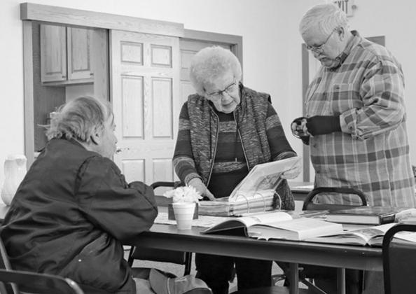 Pictured left to right are Tim Bloomquist, Marlys Nelson, and Steve Marten looking through the book of memories and pictures that Marlys compiled for the project. VNV Photo by Lesa Van Camp