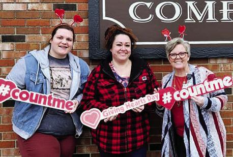 Kayce Schlittenhard, Danielle Balli, and Gwen Zorn pose in front of 1878 Grocery Company for Giving Hearts Day.