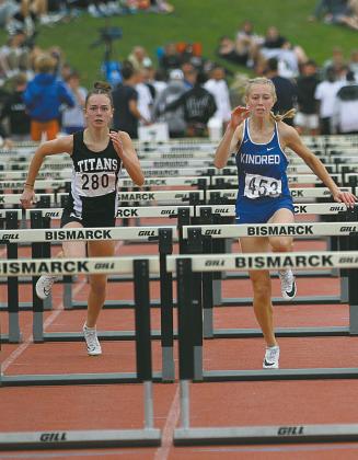 Freshman Jocelyn Vold, left, races alongside Kindred’s Ashley Haas during the preliminaries in the Class B Girls’ 100 meter Hurdles Friday. Vold qualified for the finals and finished in Seventh Place overall with a time of :16.03. Photo by Mike Alan Steinfeldt