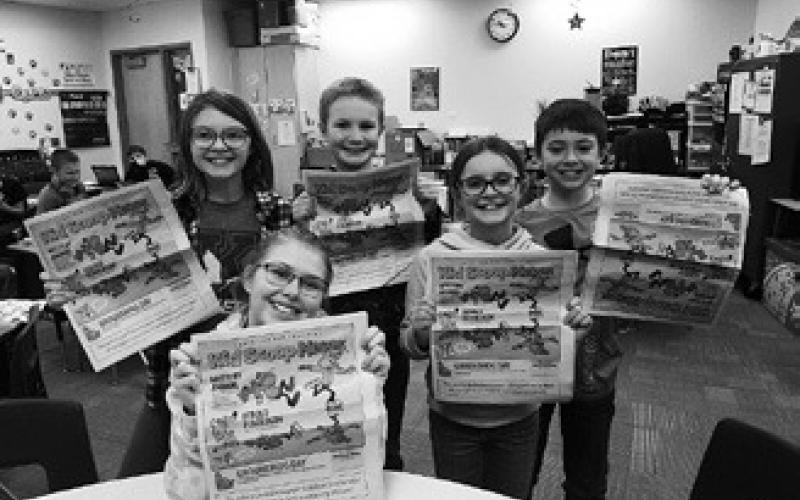 Fourth graders at Kenmore Elementary proudly display a recent copy of Kid Scoop News. From left: Ava Keysor, Connor Petersen, Hannah Alexander, and Beau Hanson. Adley Jensen (sitting front). Photo by Terry Froseth, The Kenmare News.