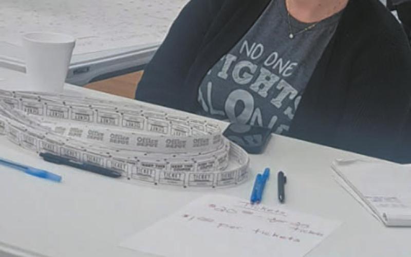 Wearing her “No one fights alone” t-shirt, Kayla Thompson helped sell tickets for the silent auction held during the Pollestad fundraiser last weekend in Drayton. Photo by Christine Jensen