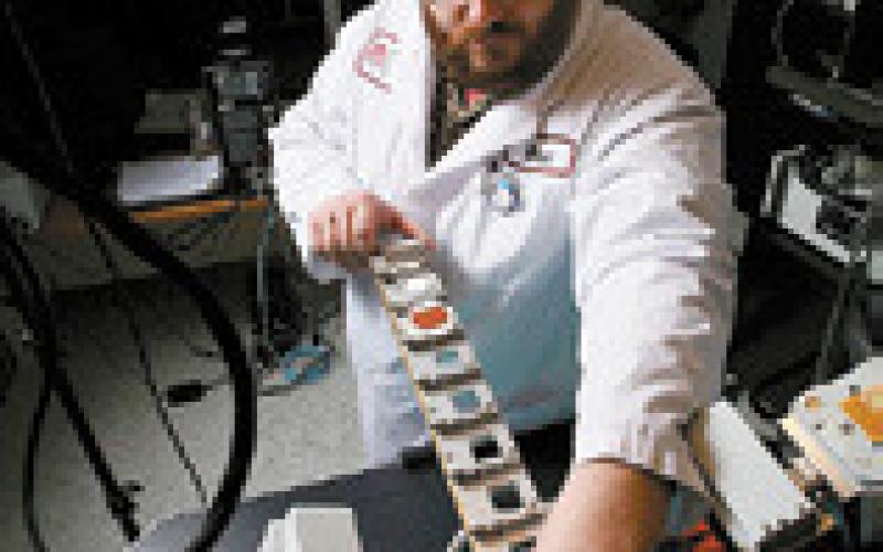 EERC materials scientist Blaise Mibeck loads samples for testing in a system used for evaluating critical mineral concentrations.