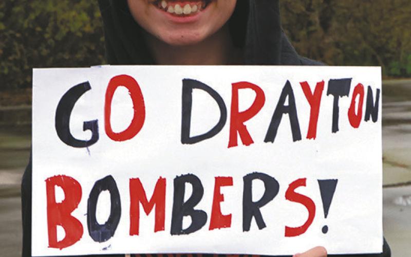 Ruthie Rarick holds up a sign supporting the team as they head for Minot. Photo by Lyle Van Camp