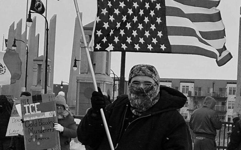 Jerrod Baetsch of West Fargo, North Dakota, stands with an American flag upside down, a sign of distress, on the Veterans Memorial Bridge over the Red River in Fargo on Jan. 10, 2026. Photo by Jeff Beach/North Dakota Monitor