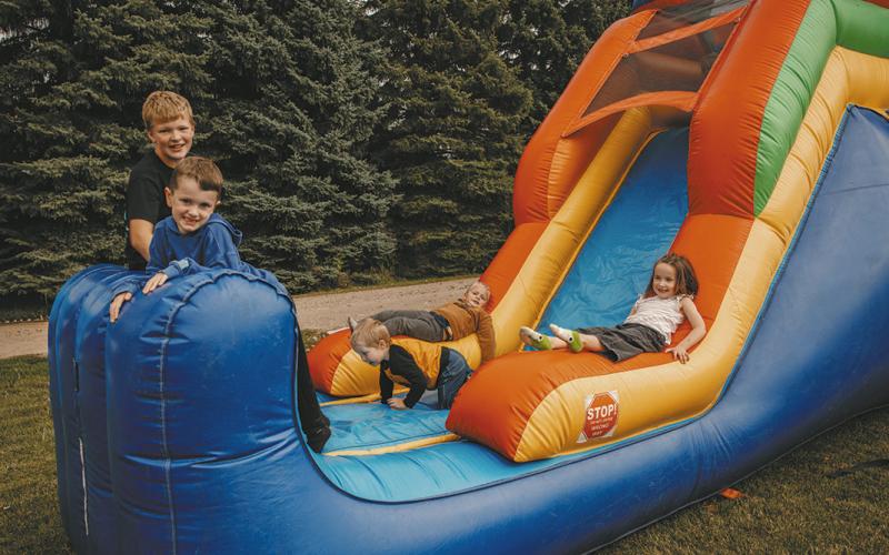 Hunter Gullickson, Emmett Paulson, Ila Hall, and Beckam Evenson enjoy the bounce houses with a toddler.