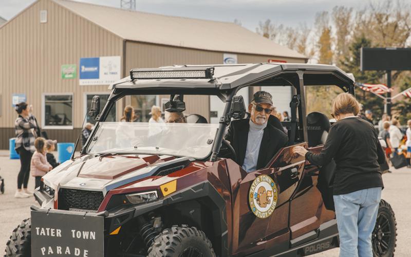 Loren Gullickson driving the ATV for the Parade Grand Marshall's, The Hoople Study Club while refilling Sue Fagerholts treat bag to pass out candy.