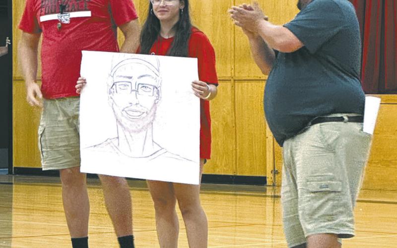 Coach Foster admires Allison Chavez's drawing of him while coach Smith applauds her work. Photo by Lyle Van Camp