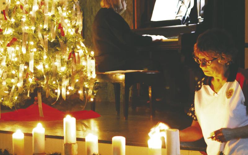 Kristi Scharmer lights the candles while Shirley VanCamp plays in the background. Photo by Lyle Van Camp.