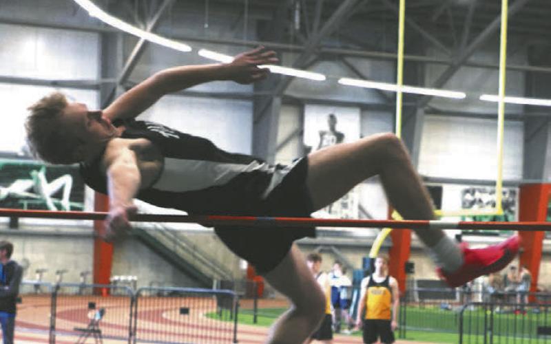 Carter Oberg fights his way over the bar in the boys high jump. Photo by Lyle Van Camp.