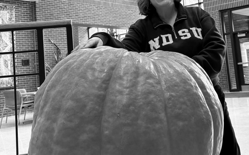 Esther McGinnis, NDSU Extension horticulturist, stands next to a giant pumpkin on the NDSU campus. NDSU photo