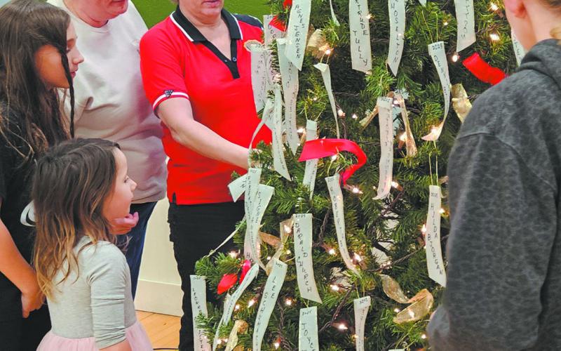 The Scharmer/Stangeland family takes a moment to gather around the tree and read names on memorial ribbons. Photo by Jamie Rarick