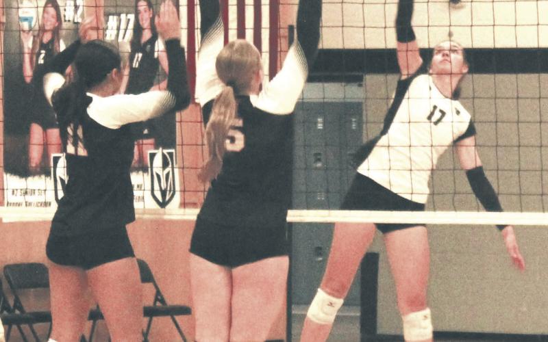 Lined up against Cavalier's Jaylynn Stegman and Katy Jensen, Elizabeth Fedje tips the ball back over the net. Photo by Jamie Rarick
