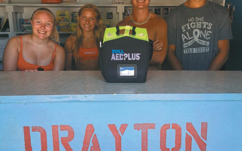Drayton Pool lifeguards (l to r) Gracie Johnson, Reese Fering, Jonathan Knudson, and Mason Pollestad stand with one of the defibrillators placed at the pool. It’s one of several being placed strategically around Drayton and is a life saving tool for prehospital treatment for cardiac arrest. Photo by Christine Jensen.
