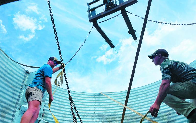 Brothers, Ryan [23, left] and Richard [19, right] Kemp, workers from South Africa on H-2A visas, prepare an old grain bin for transfer to another section of Stephanie Hatzenbuhler’s ranch just west of Mandan. Photo Michael Standaert.
