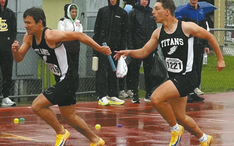 Trenten Bronson-Keena receives the baton from Carter Johnson while navigating slippery track conditions during the 4X100 relay. The team set a new school record of :44.67. Photo by Larry Stokke