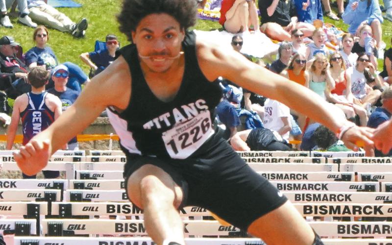 Mason Pollestad leaps over the 110-meter hurdles, placing third at the Class B State Track Meet in Bismarck. Photo by Larry Stokke