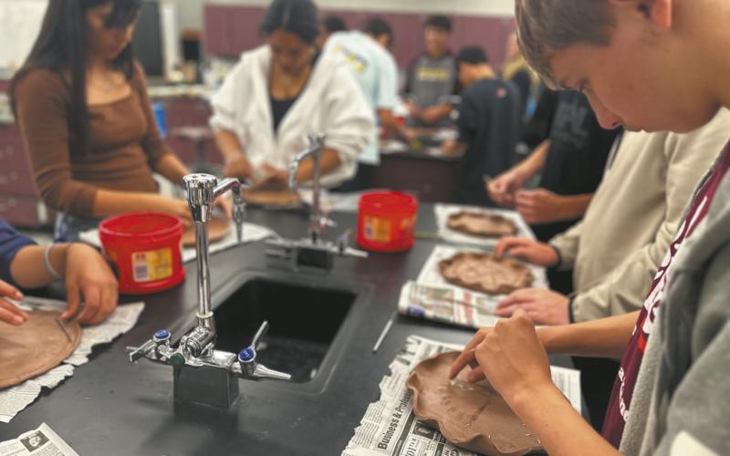 North Valley CTE students Julissa Garcia (left), Daphneiris Almonte, and Aaron Linner press prairie plants into clay plates as part of the Thinking Like a Prairie workshops. Plates will be fired and glazed and used at a potluck as part of the program next Spring. Photo Josh Anderson.