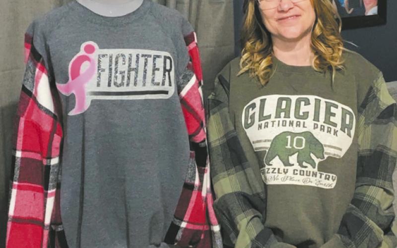 Jamie Mattice wears the first sweatshirt she created from a t-shirt she received from her daughter, Rylee, while standing next to one of her Re-Loveables sweatshirts. Photo by Rylee Maurstad
