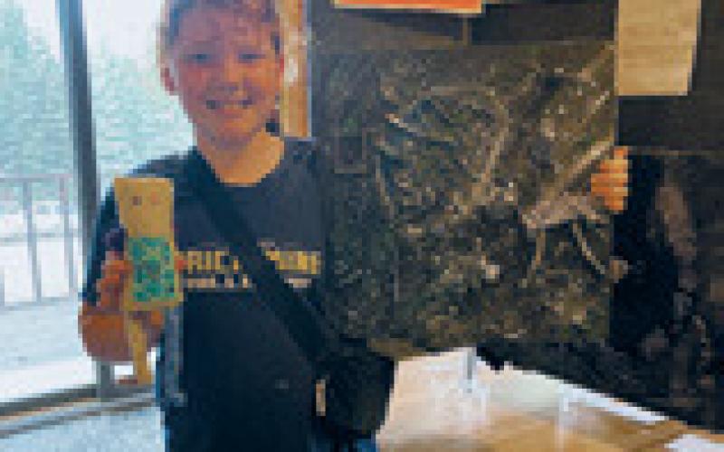 Stella Busse shows off her junk sculpture at the Encore Art Camp. Photo by Jessica Tull.