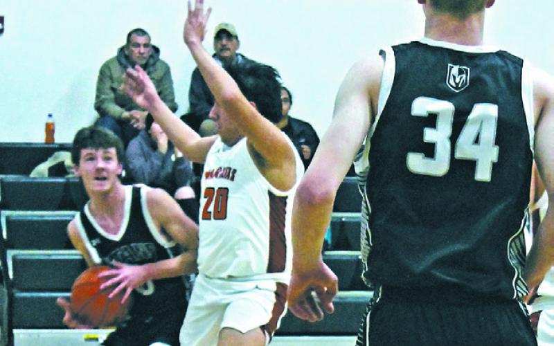 In a drive to the basket, Brady Reilly pushes past Warrior defender Elijah Feather, Jr. Photo by Jamie Rarick.