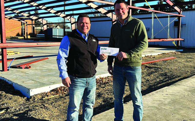 Polar Board Member Dan Johnson (left) presents a check to Hoople Community Fund Committee Member Jeff Olson (right) while standing on the construction site of the new Community Center being built in Hoople.