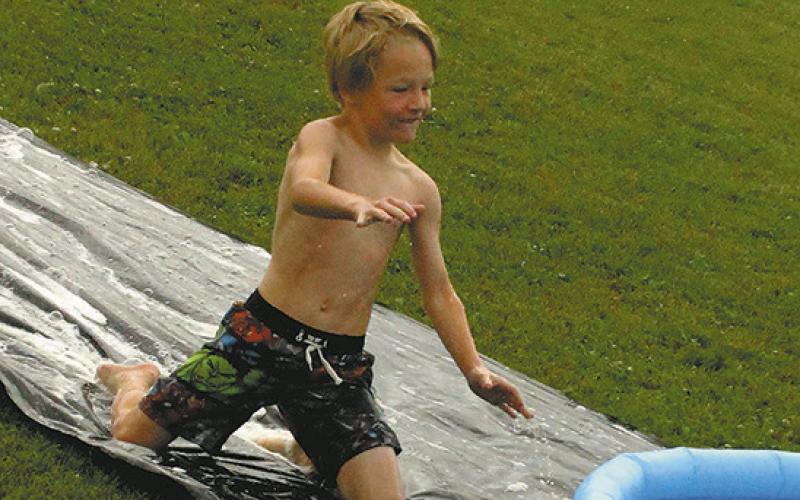 Canaan Smith slides into home at Friday's Slip 'N Slide kickball game at Schumacher Park.Photo by Jamir Rarick