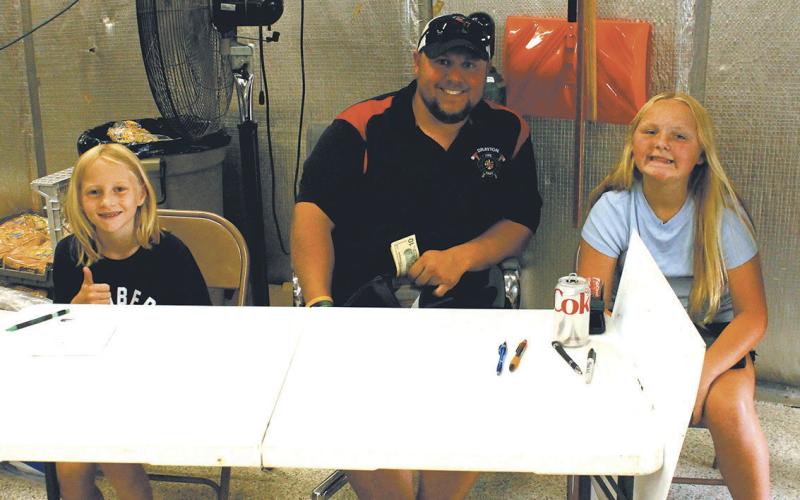 Drayton fire chief Jordan Grundstrom with helpers Charlotte Schumacher and Marissa Grundstrom greeted guests at the door for Thursday's burger night. Photo by Jamie Rarick
