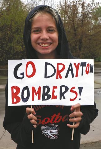 Ruthie Rarick holds up a sign supporting the team as they head for Minot. Photo by Lyle Van Camp