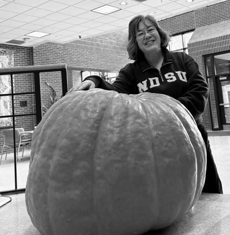 Esther McGinnis, NDSU Extension horticulturist, stands next to a giant pumpkin on the NDSU campus. NDSU photo