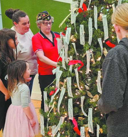 The Scharmer/Stangeland family takes a moment to gather around the tree and read names on memorial ribbons. Photo by Jamie Rarick