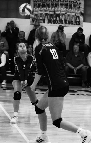 Junior Claire Thompson (3) passes the ball as sophomore Easton Larson gets ready to hit in Friday's final match of the year vs. North Border in Pembina. Photo by Mike Alan Steinfeldt.