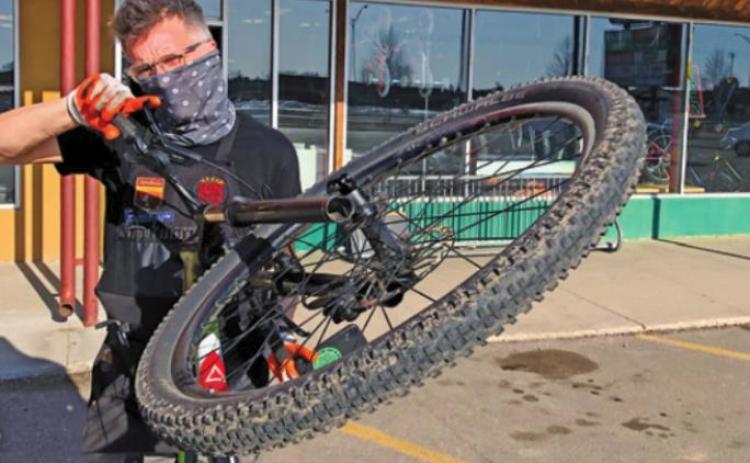 Pat White wears a mask as he wrestles with a bicycle at his Grand Forks business, The Ski and Bike Shop, which has felt the effects of a nationwide bike shortage due at least in part to the COVID-19 pandemic. Photo submitted