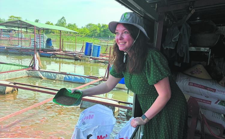 Billie Lentz of Perth tried her hand feeding fish at an aquaculture operation. ND Soybean Council photo