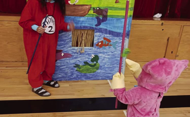 Tess Sehrt helps Elsie Littlejohn play a ‘fishing’ game on Saturday.