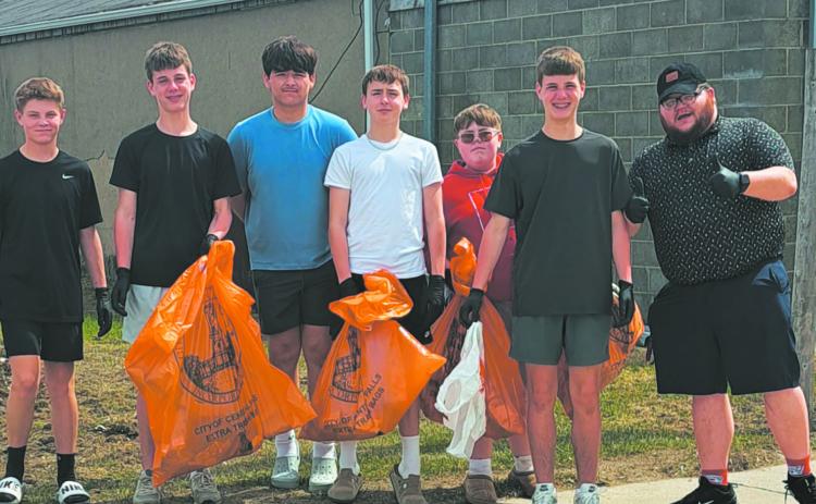 Mr. Riddle gives a thumbs up as his group shows off their bounty of collected trash. Photo by Christine Jensen