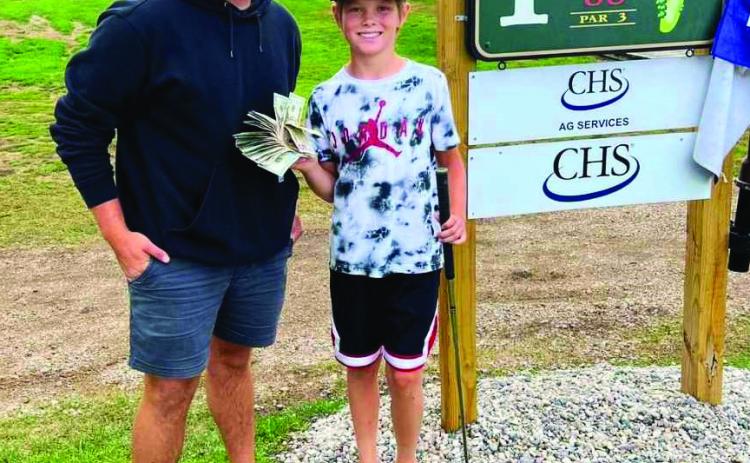 Tyber Pokrzywinski and Asher McFarland pose at hole #1 with Asher’s winnings. Photo by Genafay Pokrzywinski.