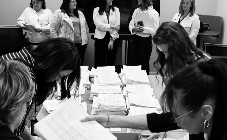 Members of the sponsoring committee for a proposed ballot measure to make public school meals free watch as staff with the North Dakota Secretary of State’s Office count petition signatures on April 9, 2026. (Photo by Mary Steurer/North Dakota Monitor)