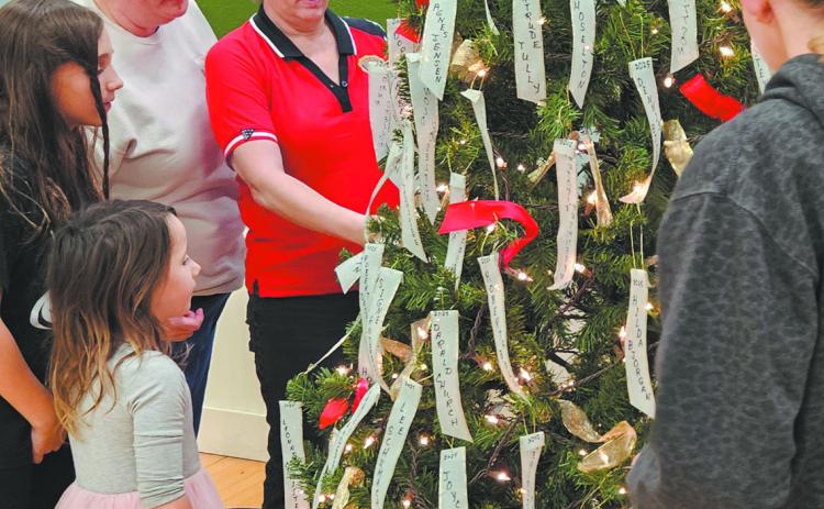 The Scharmer/Stangeland family takes a moment to gather around the tree and read names on memorial ribbons. Photo by Jamie Rarick