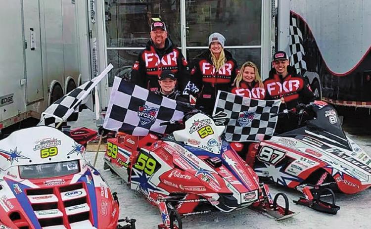 Hunter Johnson pictured with his three championship flags and the Johnson Racing sleds. Pictured left to right Hunter Johnson, Scott Johnson (back), Amber Johnson, Madison Phillips, and Jaden Haagenson Photo submitted by Johnson Racing
