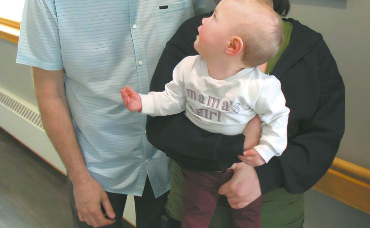 Baby Allara looks back and smiles at Dr. Joel Johnson while being held by her mother, Samantha Kartes. Submitted photo