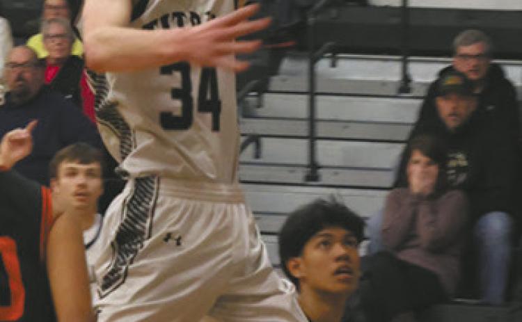 Soaring through the air, DVE senior Jack Langerud extends for the basket against Warwick Warrior defenders Feb. 20 on his home court. Photo by Jamie Rarick