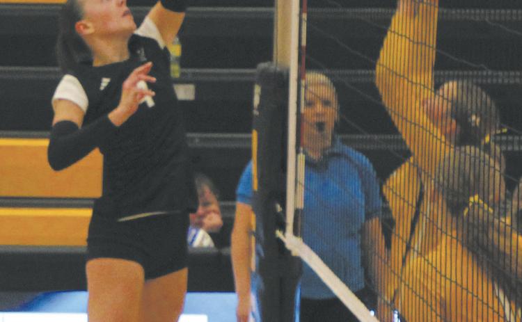 Extending over the net, DVE junior Jocelyn Vold tips the ball against Park River defenders. Photo by Jamie Rarick